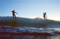 two surfers riding a wave in the ocean